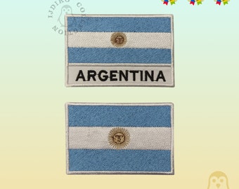 Könnte beinhalten: Zwei gestickte Aufnäher mit der argentinischen Flagge. Der obere Aufnäher hat das Wort "ARGENTINA" unter der Flagge. Beide Aufnäher haben einen weißen Hintergrund und blaue und weiße Streifen.