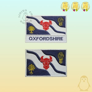 May include: Two embroidered patches featuring the flag of Oxfordshire, England. The top patch has the words "OXFORDSHIRE" embroidered below the flag. The bottom patch is just the flag.