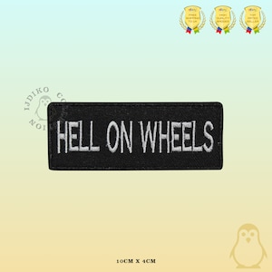 Op de afbeelding: Zwarte geborduurde patch met witte tekst die "HELL ON WHEELS" luidt. De patch is 10 cm bij 4 cm.