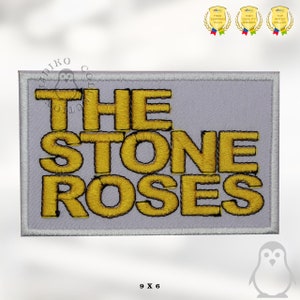 Może przedstawiać: Biała naszywka haftowana z napisem "THE STONE ROSES" w żółtej nici. Naszywka ma 9 cali na 6 cali.