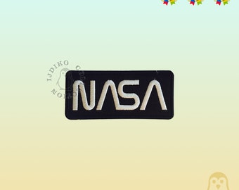 Può includere: Una toppa rettangolare nera con le lettere bianche ricamate "NASA". La toppa misura 9,8 cm x 4,3 cm. Questo è un articolo a tema esplorazione spaziale.