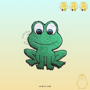 May include: Green embroidered iron-on patch of a cartoon frog with white eyes and a smile. The patch is 6 cm by 7 cm.