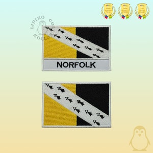 May include: Two embroidered Norfolk flag patches. The design includes a yellow quarter, a black quarter, and a white diagonal stripe with black symbols. The word "NORFOLK" is embroidered on a white rectangle below the flag design.