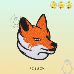 May include: An embroidered iron-on patch of a fox's head with a white muzzle and orange fur. The fox is looking to the right and has a serious expression. The patch is 7 cm by 5.5 cm.