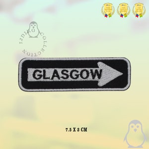 May include: Black and white embroidered patch with a white arrow pointing right and the word "GLASGOW" in white text. The patch is 7.5 cm by 3 cm.