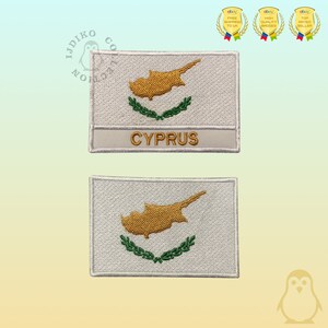 May include: Two white embroidered patches with the flag of Cyprus. The top patch has the word "CYPRUS" written below the flag.