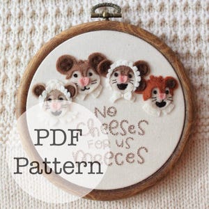 May include: An embroidered felt hoop with four cartoon mice. The mice have brown and white fur, pink noses, and smiling faces. The text "No Cheeses For us Miceces" and "PDF Pattern" are embroidered on the white fabric.