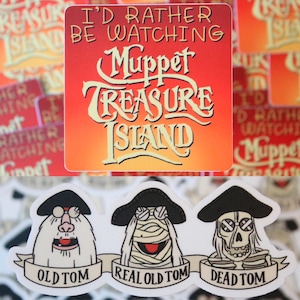 May include: A collection of stickers with a Muppet Treasure Island theme. One sticker displays the text "I'd Rather Be Watching Muppet Treasure Island". Below are three stickers of the character "Old Tom", each in a different form.