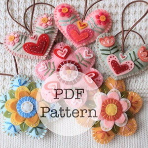 May include: A collection of handmade felt ornaments in heart and flower shapes. The hearts are in shades of pink, red, and cream, with embroidered details and brown hanging loops. The flowers are in shades of blue, yellow, and pink. The text "PDF Pattern" is overlaid.