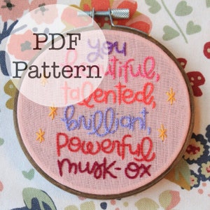 May include: A pink fabric embroidery hoop with the words "You Beautiful, Talented, Brilliant, Powerful Musk-Ox" stitched in various colors. The text "PDF Pattern" is overlaid on the image.