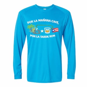 May include: A turquoise long-sleeve shirt with the text "POR LA MAÑANA CAFÉ, POR LA TARDE RON." The design includes a coffee cup, palm trees, a star, a glass of whiskey, and the Puerto Rican flag.