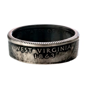 May include: A silver-toned ring made from a West Virginia quarter. The ring features the words "West Virginia 1863" on the band.