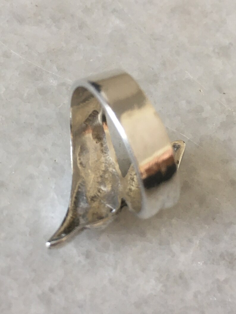 May include: Silver ring featuring a stylised bird design. The ring is open and has a smooth, polished finish.