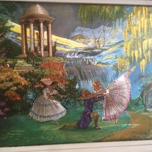 Op de afbeelding: Een vintage ingelijst kunstwerk dat een fantasierijke sc&egrave;ne met drie dansers in een tuinsetting toont. De dansers zijn gekleed in kleurrijke kostuums en voeren een balletroutine uit. De achtergrond toont een waterval, een prieel en weelderig groen.