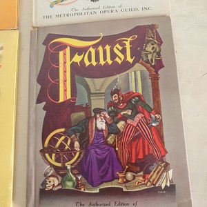 May include: A vintage book cover featuring an illustration of a man with a white beard and a red devil. The book title is "Faust" and the text "The Authorized Edition of THE METROPOLITAN OPERA GUILD, INC." is printed on the cover.