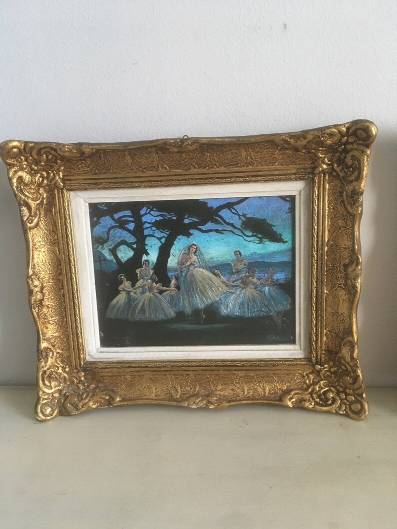 Op de afbeelding: Een ingelijst kunstwerk dat een groep ballerina's in witte tutu's toont die onder een boom dansen in een blauwe en paarse schemering.