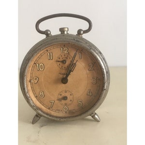 Vintage Diehl Alarm Table Clock Mechanical Hand Winding-Made In Germany. Silver Color Timeworn Patina. Working Order but not 100% accurate.