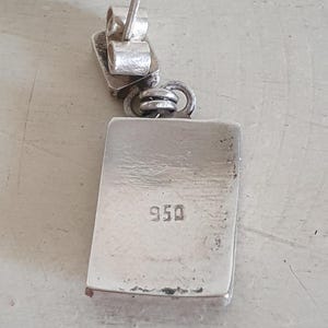 May include: Silver earring with a rectangular pendant marked "950".