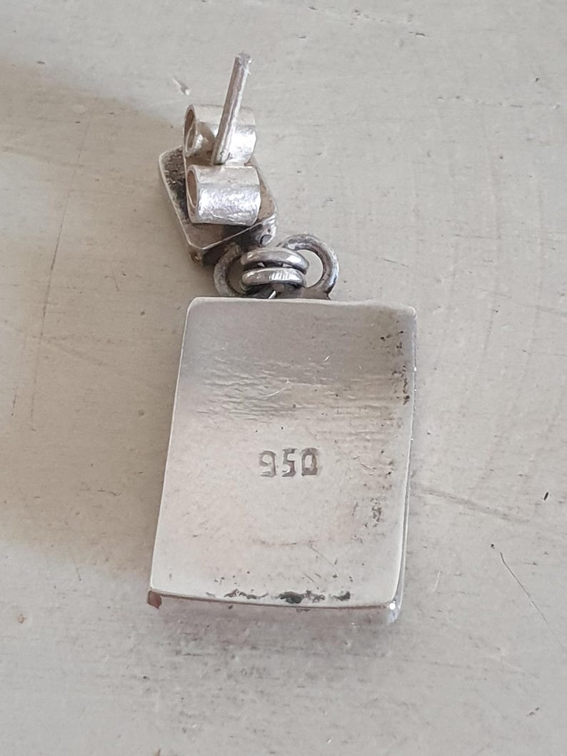 May include: Silver earring with a rectangular pendant marked "950".
