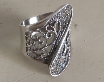 Puede incluir: Un anillo de filigrana de plata con un diseño en forma de lágrima y pequeñas piedras transparentes.