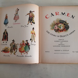 May include: An illustrated book cover for a children's adaptation of the opera Carmen by Bizet. The cover features a colorful illustration of a woman in a red dress and a man in a black and white suit. The title "Carmen" is written in large, bold letters at the top of the cover. The book is published by Grosset & Dunlap.