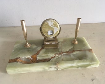 Op de afbeelding: Een groene marmeren bureauset met twee gouden pennenhouders en een gouden globekalender met het getal 9.