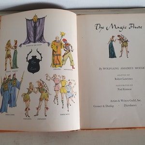 May include: An illustrated book cover for a children's adaptation of The Magic Flute opera by Wolfgang Amadeus Mozart. The cover features a colorful cast of characters from the opera, including the Queen of the Night, Sarastro, and Papagena.