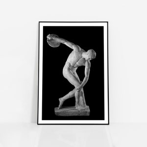May include: Black and white photograph of a marble statue of a discus thrower against a black background.