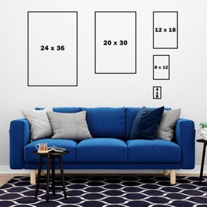 Op de afbeelding: Een blauwe bank met drie kussens en een zwarte bijzettafel met een boek en een kopje erop. Er hangen vijf ingelijste foto's aan de muur achter de bank. De foto's zijn van verschillende groottes en hebben zwarte lijsten. De foto's hebben de volgende afmetingen: 61 x 91 cm, 51 x 76 cm, 30 x 46 cm, 20 x 30 cm en 10 x 15 cm.