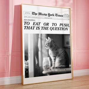 May include: A black and white photo of a cat looking at a jar of cat food. The photo is framed in a gold frame and has a newspaper headline that reads "The Meow York Times" and "Zen Dilemma: To Eat or To Push, That Is The Question".