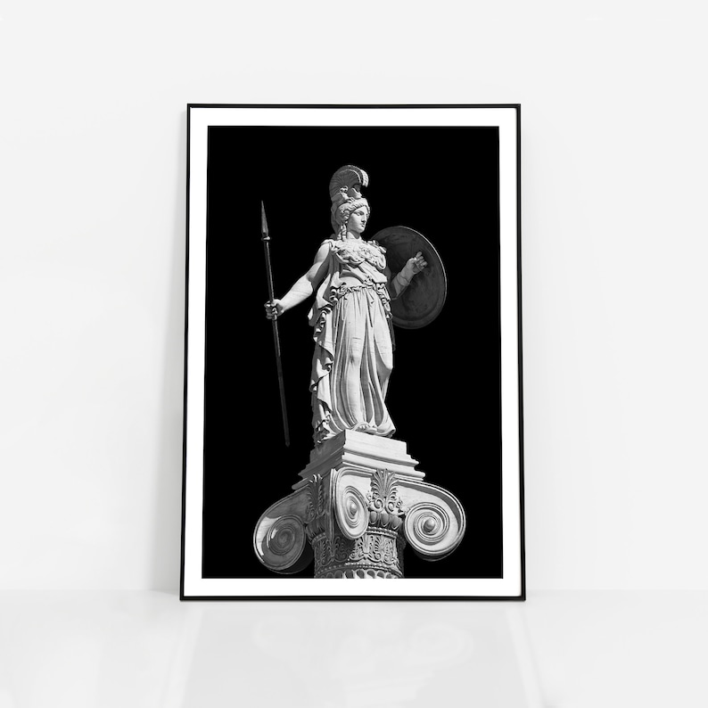 Op de afbeelding: Zwart-witfoto van een standbeeld van een vrouwelijke krijger die een speer en schild vasthoudt. Het standbeeld staat op een kolom met sierlijke details. De achtergrond is zwart.