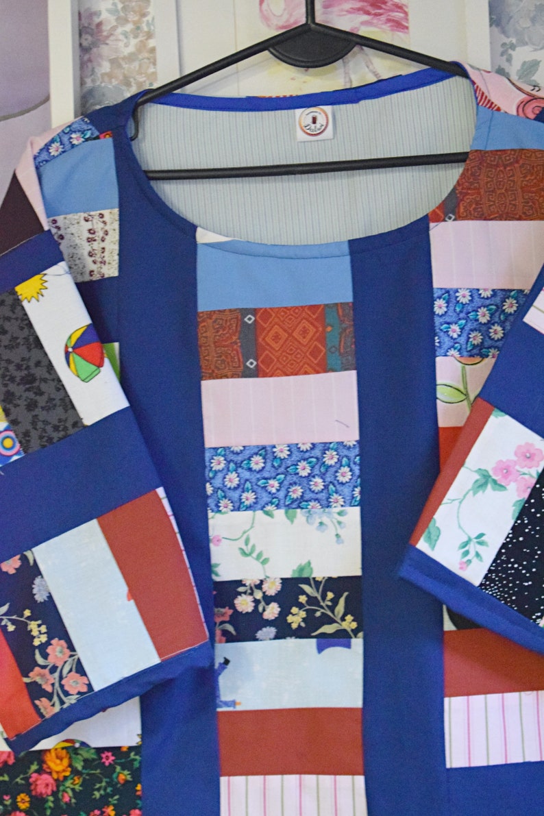 May include: A blue patchwork shirt with a variety of colorful fabric squares. The shirt has a round neckline and short sleeves. The fabric squares feature floral patterns, geometric designs, and stripes.