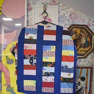 May include: A blue patchwork jacket with a variety of colorful fabrics and patterns. The jacket is made of different pieces of fabric sewn together to create a unique and interesting design.