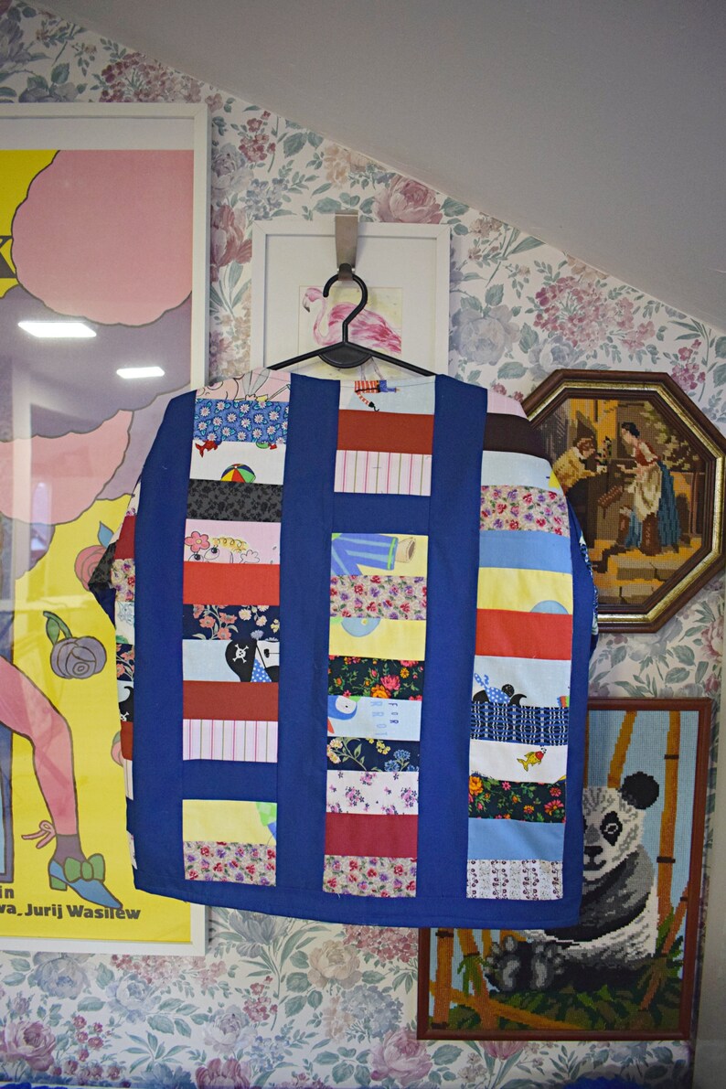 May include: A blue patchwork jacket with a variety of colorful fabrics and patterns. The jacket is made of different pieces of fabric sewn together to create a unique and interesting design.
