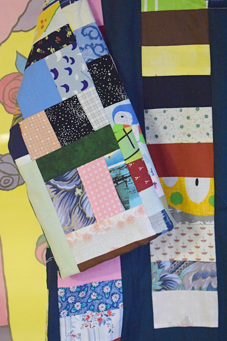 Puede incluir: Una tela de patchwork azul y blanca con una variedad de patrones, que incluyen lunares, rayas y dise&ntilde;os florales. La tela est&aacute; cosida en un patr&oacute;n de cuadr&iacute;cula y tiene un borde verde claro.