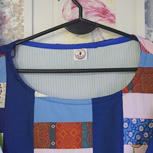 May include: A blue patchwork top with a white and green striped lining. The top has a round neckline and a label that says "Dalia's".