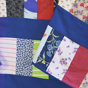 Puede incluir: Una colcha de retazos con una variedad de telas coloridas, incluyendo azul, rojo, verde y blanco. La colcha est&aacute; hecha de cuadrados y rect&aacute;ngulos de diferentes tama&ntilde;os y patrones. La colcha es un gran ejemplo del arte del acolchado.