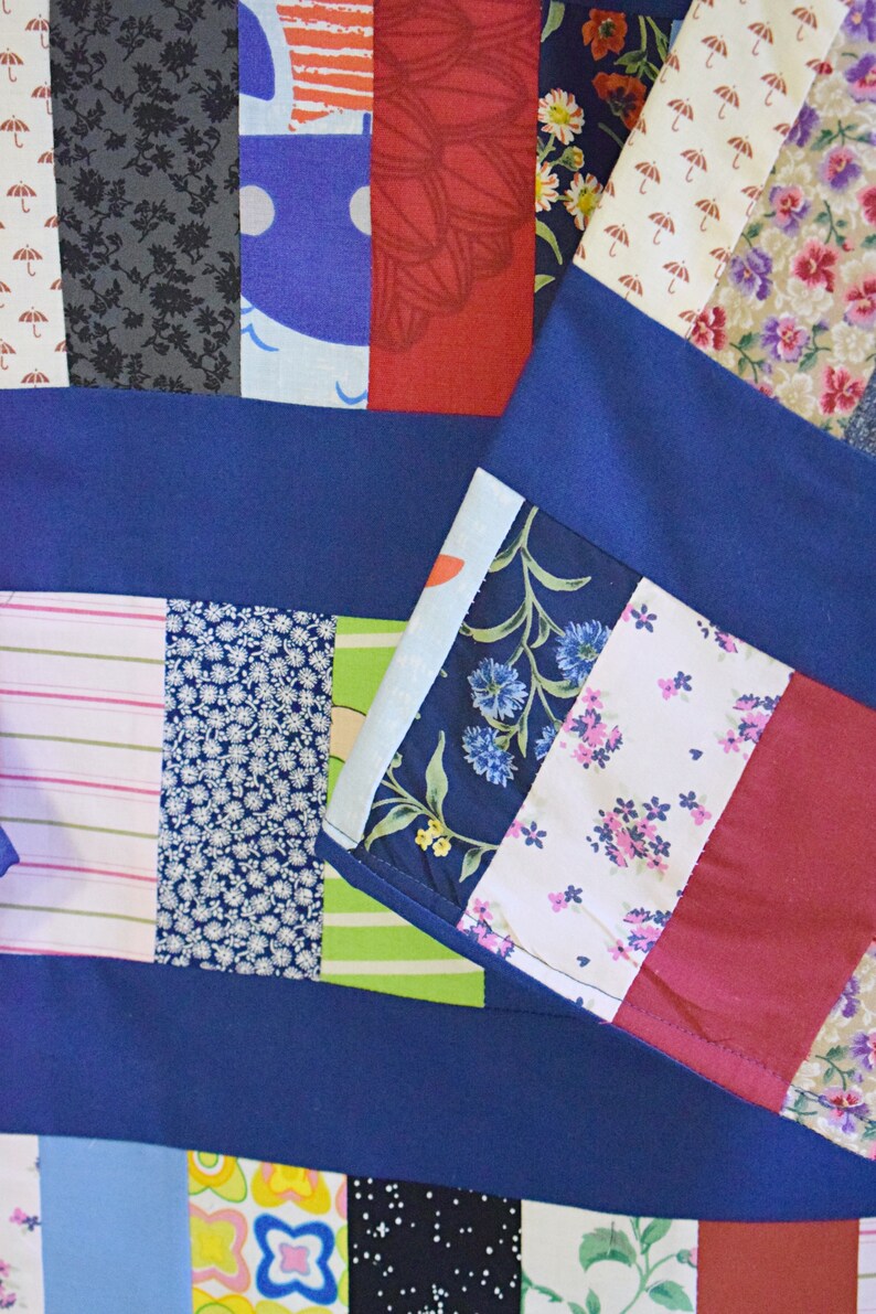 Puede incluir: Una colcha de retazos con una variedad de telas coloridas, incluyendo azul, rojo, verde y blanco. La colcha est&aacute; hecha de cuadrados y rect&aacute;ngulos de diferentes tama&ntilde;os y patrones. La colcha es un gran ejemplo del arte del acolchado.