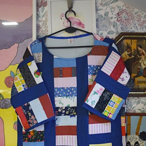 May include: A blue patchwork top with a variety of colorful fabrics, including floral prints, stripes, and geometric patterns. The top has a round neckline and three-quarter sleeves.