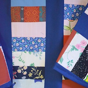 May include: A blue patchwork shirt with a variety of colorful fabric patterns, including floral, geometric, and striped designs.