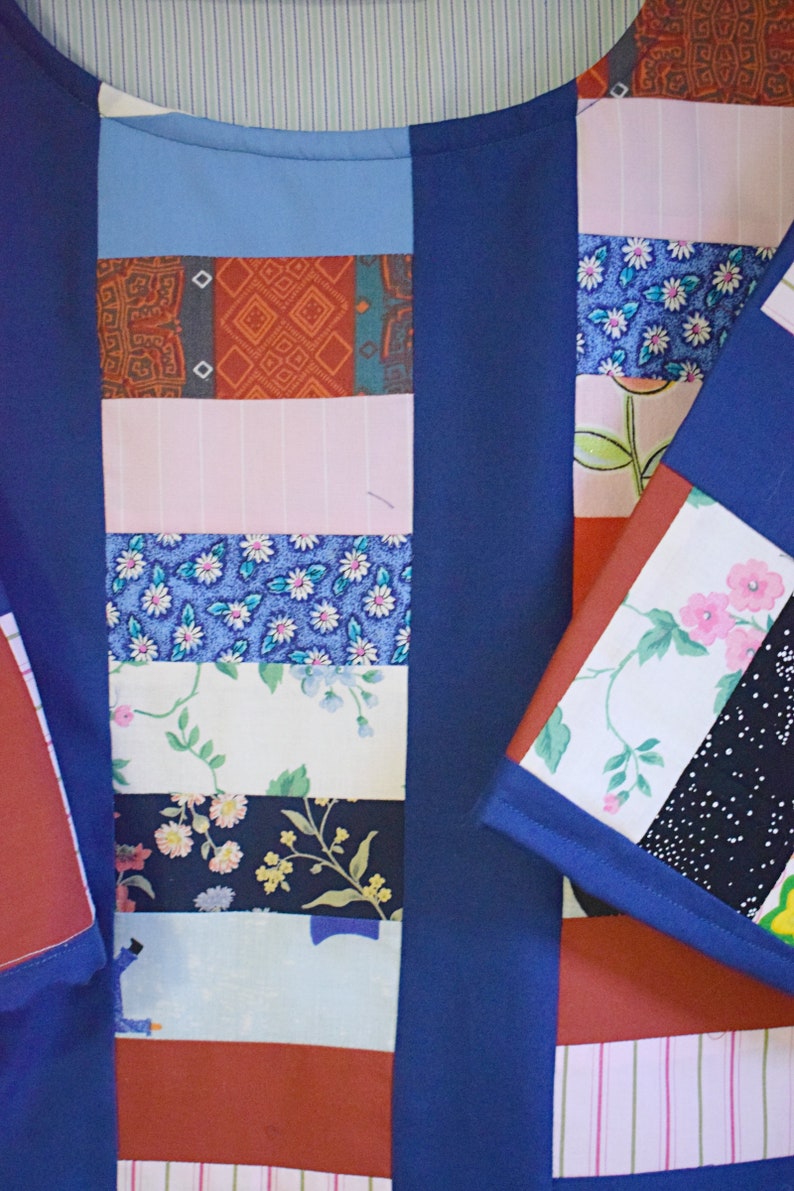 May include: A blue patchwork shirt with a variety of colorful fabric patterns, including floral, geometric, and striped designs.