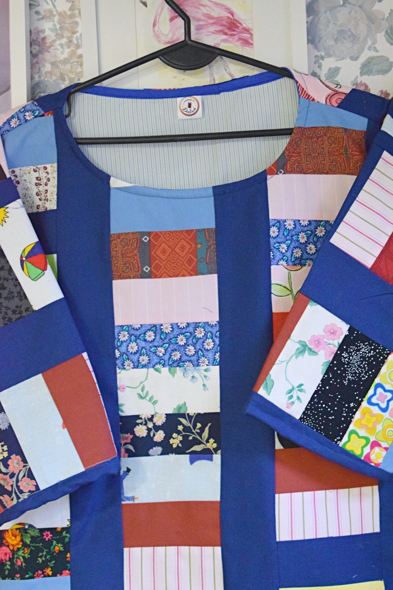 May include: A blue patchwork shirt with a variety of colorful fabrics, including floral prints, stripes, and geometric patterns. The shirt has a round neckline and short sleeves.