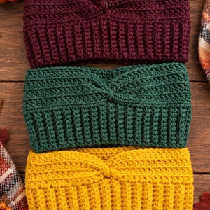 May include: Three crocheted headbands stacked vertically, each featuring a central twist detail and a ribbed texture. The top headband is deep burgundy, the middle is forest green, and the bottom headband is a vibrant mustard yellow color.