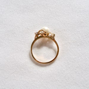 May include: A gold ring with a pearl and small diamonds set in a delicate floral design.
