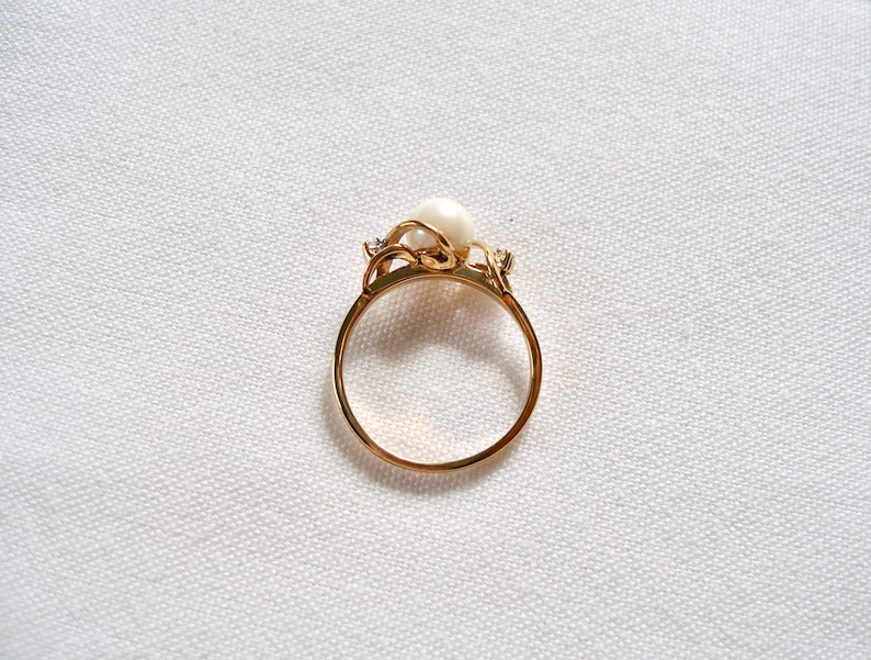 May include: A gold ring with a pearl and small diamonds set in a delicate floral design.
