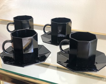 May include: Set of four black octagonal ceramic coffee cups and saucers. The cups and saucers are all the same size and shape.