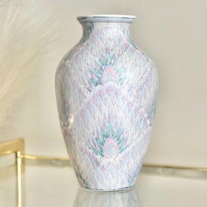 May include: A white ceramic vase with a delicate, abstract pattern of pink, blue, and green feathers. The vase has a rounded body and a slightly flared opening.