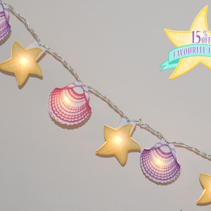 May include: A string of fairy lights with seashell and starfish shapes. The lights are white and the shapes are yellow, pink, and purple.