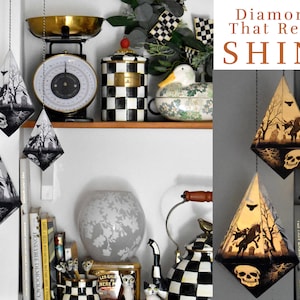 Puede incluir: Lámparas colgantes en forma de diamante con una escena de cementerio de Halloween, calaveras y siluetas de árboles. Las lámparas están suspendidas por cuerdas negras. El texto "Diamonds That Really SHINE" es visible.