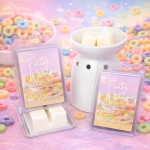 May include: Two clear plastic containers of soy blend wax melts labeled "Fruity Whirls" with a bowl of colorful cereal on the label. A white ceramic wax warmer holds two wax cubes. The background is filled with colorful cereal.